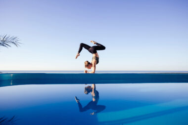 Frau die an einem Schwimmbad Yoga macht