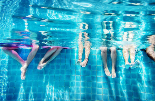 Beine von fünf Menschen unter Wasser in einem Schwimmbecken
