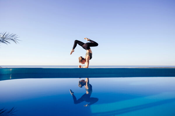 Frau die an einem Schwimmbad Yoga macht